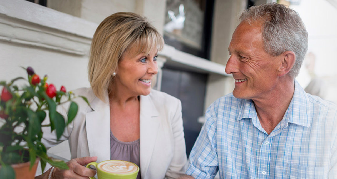 Smiling older couple outside with coffee