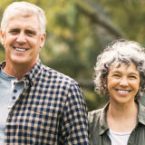 older attractive couple outside in park smiling