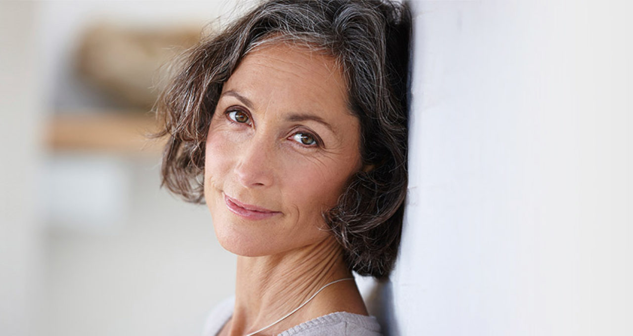 older woman leaning against wall