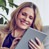 Woman using her tablet on the sofa and smiling