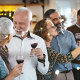 Two happy, mature couples drinking red wine and enjoying a singles dating event.