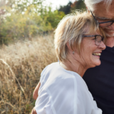 Happy 50+ couple smiling and embracing each other after meeting on a dating site containing women seeking men.