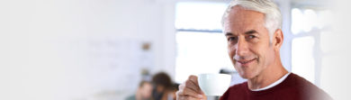 grey haired man inside drinking tea