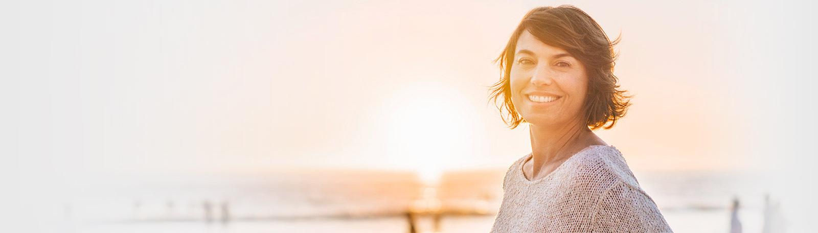 pretty brown haired woman with sunset behind her