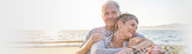elderly couple on the beach hugging