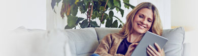 Woman using her tablet on the sofa and smiling